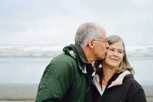 An older man kisses his partner on the cheek