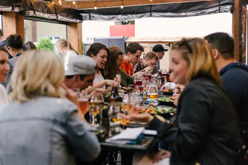 A group of people surround a dining table laughing and enjoying each others company