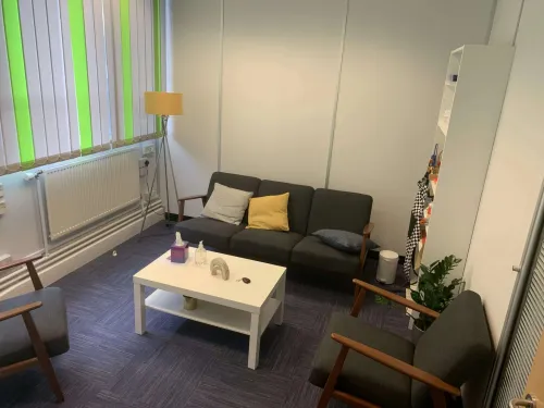 a small counselling oom with a sofa and two armchairs. there are cushions and plant placed around the room.