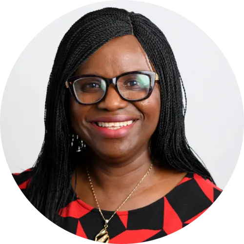 An image of Funke Fatunla - she is smiling at the camera and wearing a black and red top and black rimmed glasses.